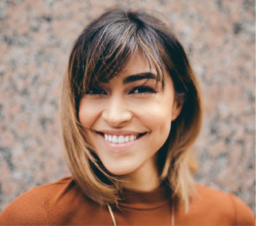 young woman smiles showing off her dental veneers