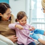 child siting in dental chair with mother, healthy habits, dental habits, child's smile