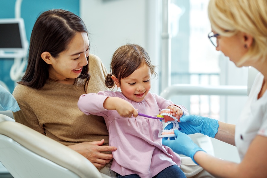 child siting in dental chair with mother, healthy habits, dental habits, child's smile